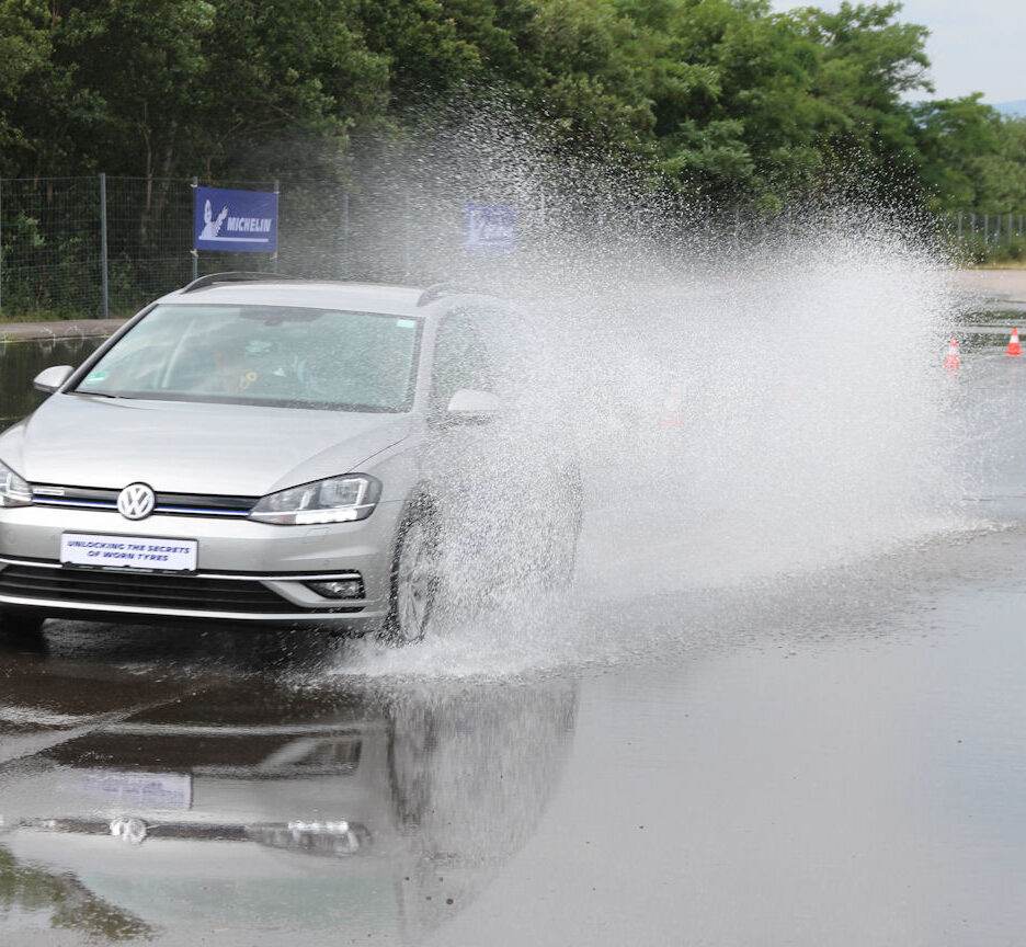 Samochód hamuje na mokrej autostradzie w deszczu, woda tryska spod kół
